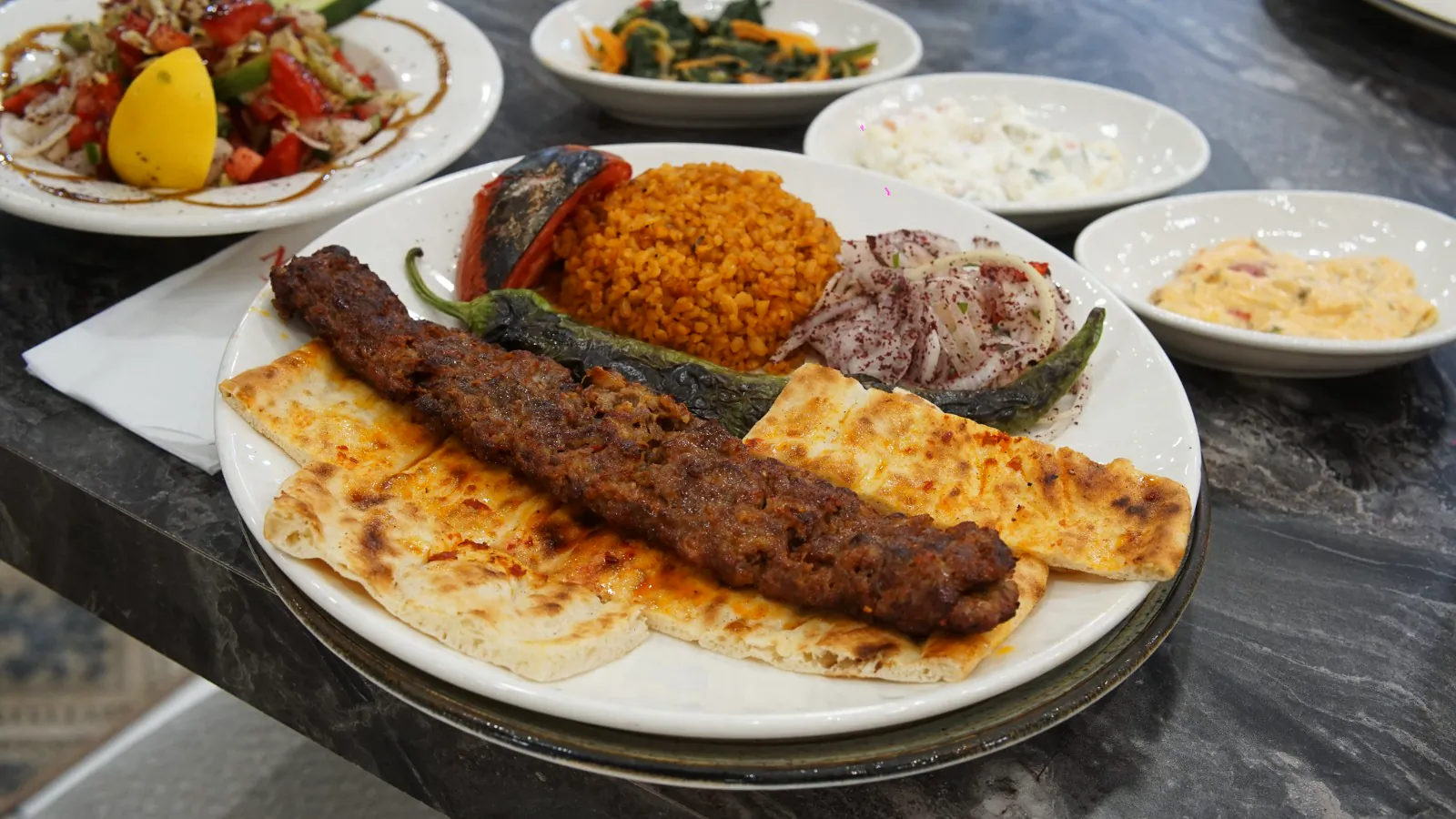 Lavaş üstünde Adana kebap, bulgur pilavı ve közlenmiş biber