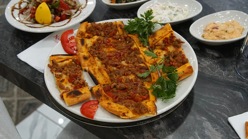 Dilimlenmiş kıymalı pide, maydanoz ve domates